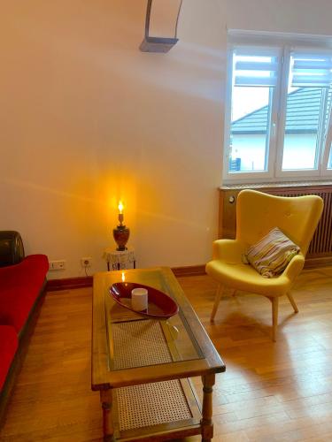 un salon avec une table et une chaise jaune dans l'établissement Gîte City Relax, entre nature et centre-ville, à Colmar