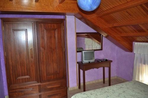 1 dormitorio con 1 cama y escritorio con TV en Apartamentos Rurales Casa Ron, en Coaña
