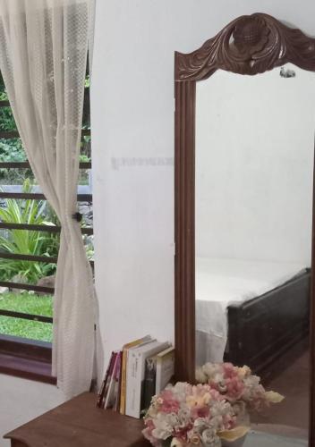 a mirror sitting on a table with books and flowers at Sun home, Hirikatiya in Dickwella