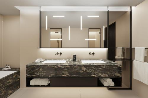 uma casa de banho com 2 lavatórios e um espelho grande em Koenigshof, a Luxury Collection Hotel, Munich em Munique