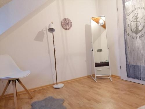 een witte kamer met een lamp en een klok aan de muur bij Ferienwohnung Fernblick in Osdorf