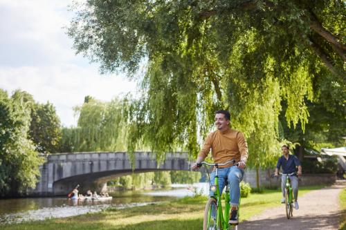 a man riding a bike down a path next to a river at Appartello Smarttime living Hamburg in Hamburg