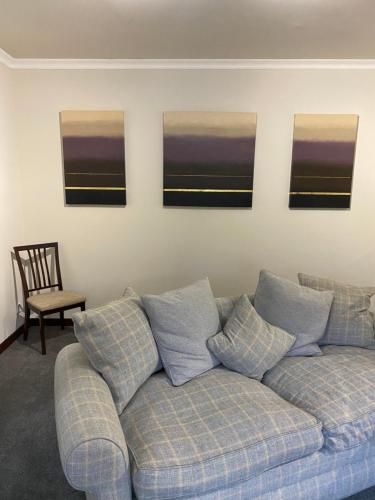 a couch in a living room with three paintings on the wall at Welltrees Apartments 14 Dailly Road Maybole in Maybole