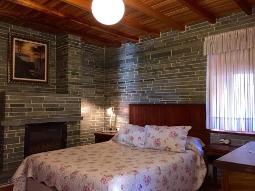 a bedroom with a bed and a brick wall at Apartamentos Rurales Casa Ron in Coaña
