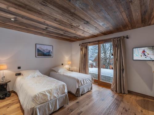 two beds in a room with a window at Le Cheval Blanc et Le Loup Blanc, jacuzzi, hammam, skis aux pieds in Méribel