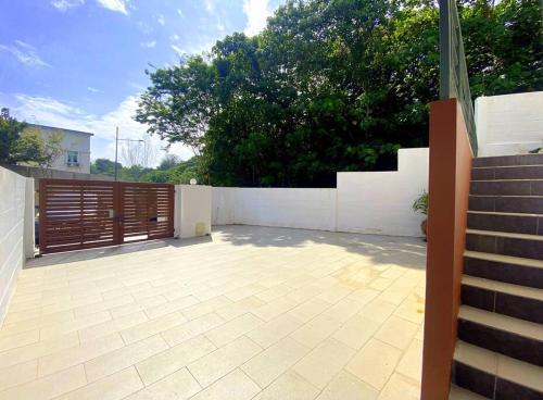 a patio with a wooden gate and a white fence at Shamrock Breeze Villa: Coastal Haven for 29 Guests in Batu Ferringhi