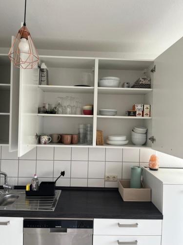 a kitchen with white cabinets with dishes in it at Ferienwohnung *Harz Raum* in Ballenstedt