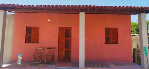 um edifício vermelho com duas cadeiras e duas janelas em Casa 2 Gold Star Village em Majorlândia