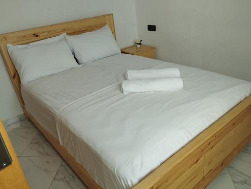 Una cama con sábanas blancas y dos toallas. en Appartement Hajar, en Oualidia