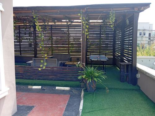 une pergola avec une table et un banc sur une terrasse dans l'établissement Frontline Homes & Suites, à Lekki