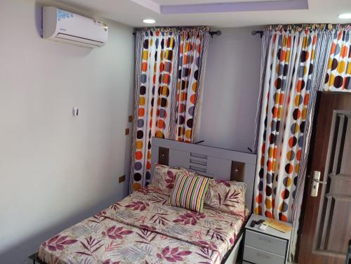 ein kleines Schlafzimmer mit einem Bett und Vorhängen in der Unterkunft Frontline Homes & Suites in Lekki
