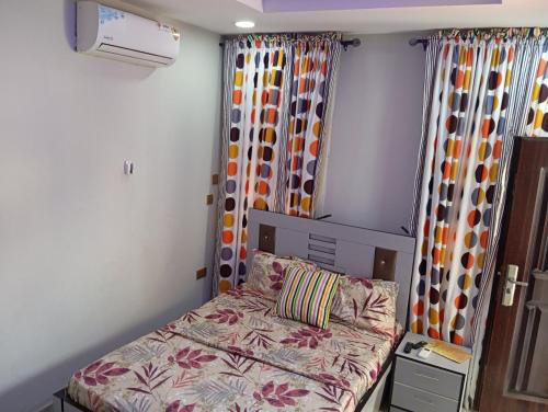 a small bedroom with a bed and curtains at Frontline Homes & Suites in Lekki