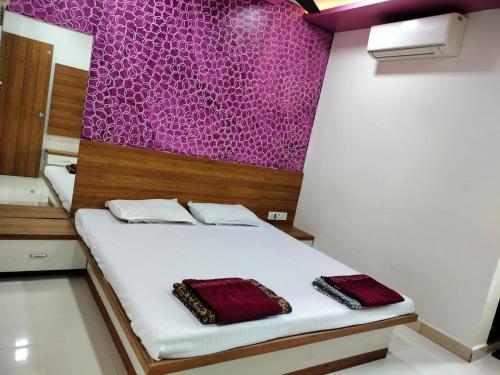Cama en habitación con pared púrpura en HOTEL SHREEJAY, en Mahād