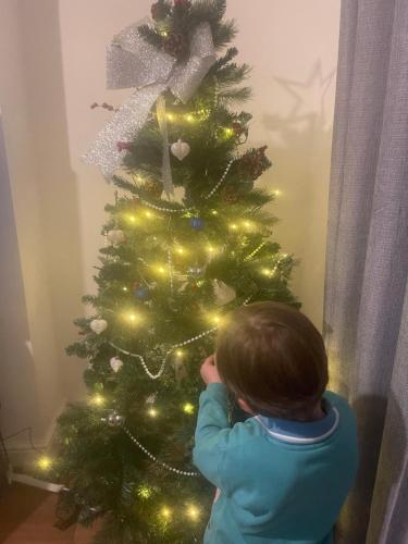 a young child standing next to a christmas tree at The Unicorn (Apartments) in Stow on the Wold