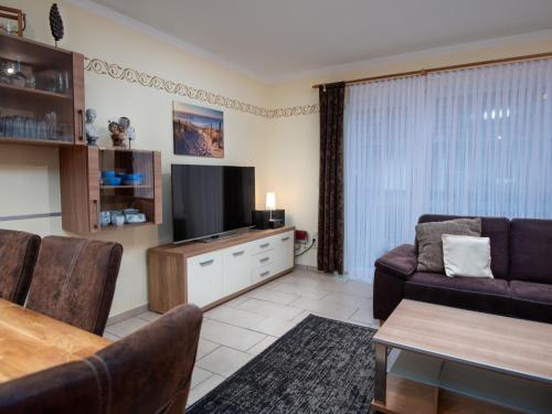 a living room with a couch and a television at Holiday Home Storchennest by Interhome in Norddeich