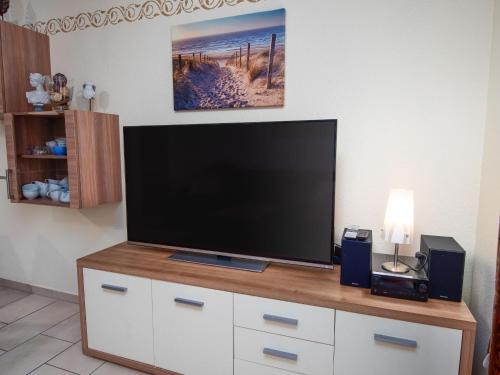 a large flat screen tv sitting on top of a dresser at Holiday Home Storchennest by Interhome in Norddeich