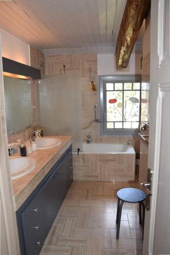 La salle de bains est pourvue de 2 lavabos, d'une baignoire et d'une fenêtre. dans l'établissement Gîte La Chênaie, maison ancienne pour 13 personnes- Clévacances 3 clés, à Castella