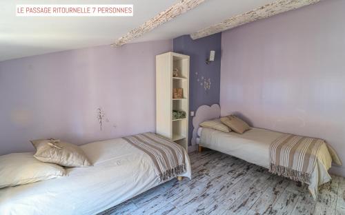 two beds in a bedroom with purple walls and wooden floors at Le Passage in Carcassonne