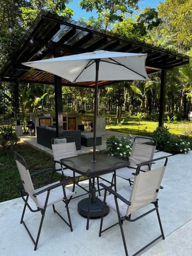 una mesa y sillas con una sombrilla en el patio en La Amapola Lodge, Bungalow en Península de Osa., en Barrigones