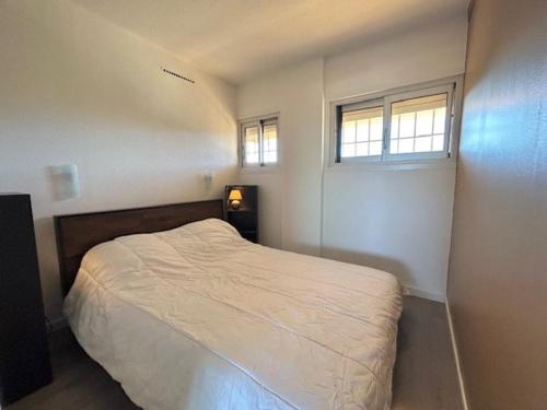 une petite chambre avec un lit et deux fenêtres dans l'établissement Appartement T2 rénové, proche plage, parking sécurisé - FR-1-388-154, à Argelès-sur-Mer
