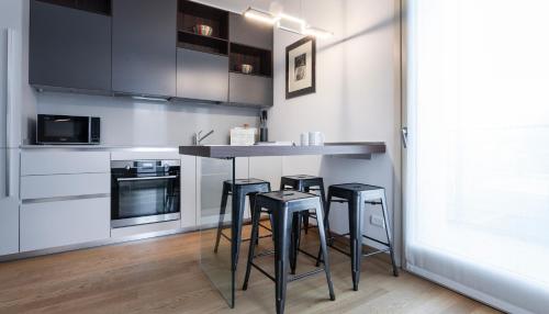 a kitchen with three bar stools and a counter at Italianway - Albani 20 in Milan