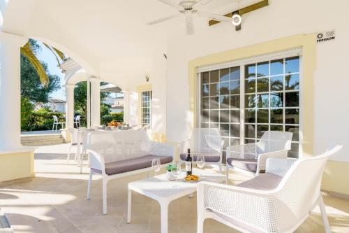 a patio with white chairs and tables and windows at Alcore Luxury Golf Villa at Alto Golf Alvor in Alvor