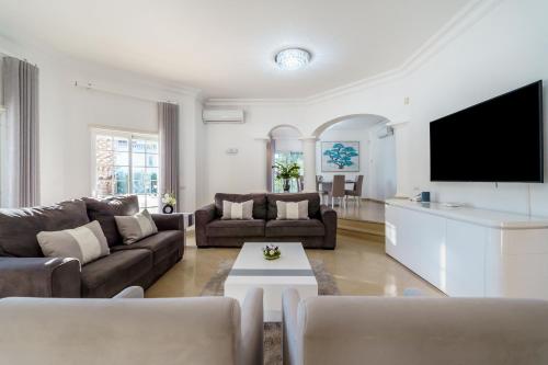 a living room with a couch and a tv at Alcore Luxury Golf Villa at Alto Golf Alvor in Alvor