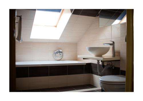 uma casa de banho com um lavatório, um WC e uma clarabóia em Wolf Panzió em Sárvár