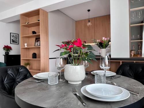 a table with plates and glasses and a vase with flowers at Balcescu Downtown Apartment in Bistriţa