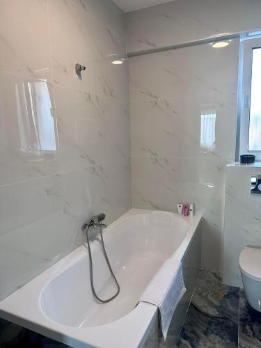 a white bathroom with a tub and a toilet at Balcescu Downtown Apartment in Bistriţa