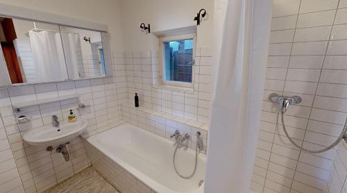 a bathroom with a tub and a sink and a shower at Ninis - Ferienhaus im Bregenzerwald in Egg