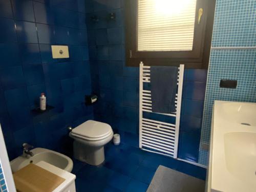 a blue tiled bathroom with a toilet and a sink at Villa The Central Tree - Lake View and Terrace in Sala Comacina