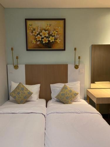 two beds in a room with a picture on the wall at The H Tower Residence by YLS Stay in Jakarta