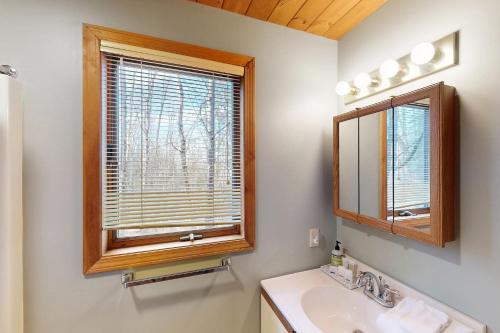 a bathroom with a sink and a mirror and a window at Trail's End in Thornton