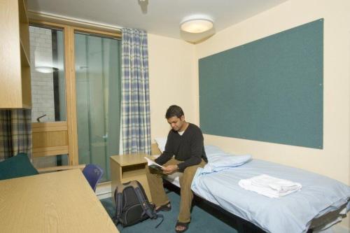 a man sitting on a bed in a room at James Lighthill House, Finsbury, London in London