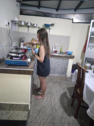 Una donna in piedi in una cucina che prepara il cibo di Guillet Beach Home a Matara