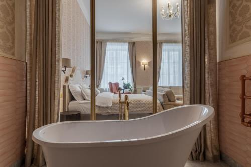 a bath tub in a bathroom with a bedroom at Hotel Unicus Palace Old Town in Kraków