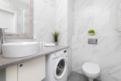 a white bathroom with a washing machine and a sink at Cozy Apartment Gdańsk Morena Rakoczego by Rent like home in Gdańsk