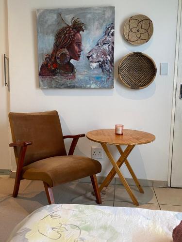 a room with a chair and a table and a painting at Nambani House in Windhoek