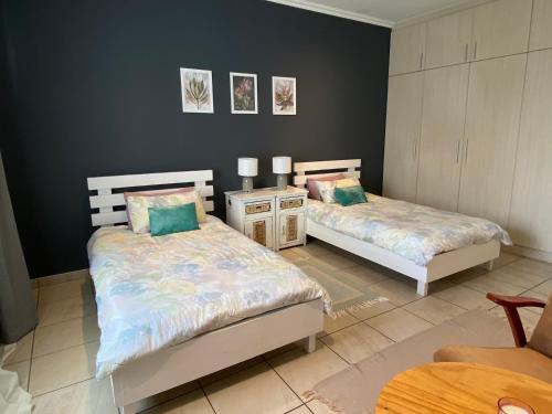 a bedroom with two beds and a table at Nambani House in Windhoek