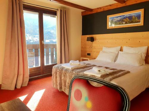 ein Hotelzimmer mit einem Bett und einem großen Fenster in der Unterkunft Chalet Hôtel du Bois in Les Houches