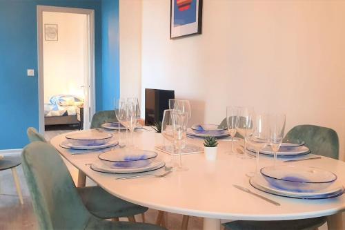 - une table blanche avec des assiettes et des verres dans l'établissement Cocon Rue Ecuyère - Calme- 2ch - 6pers, à Caen