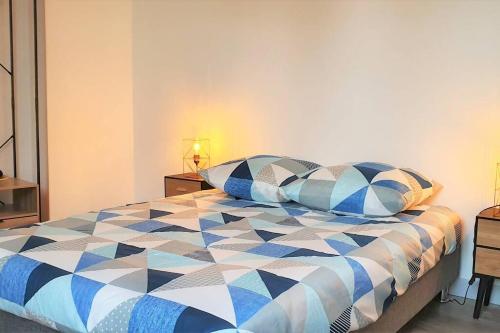 um quarto com uma cama azul e branca com almofadas em Cocon Rue Ecuyère - Calme- 2ch - 6pers em Caen