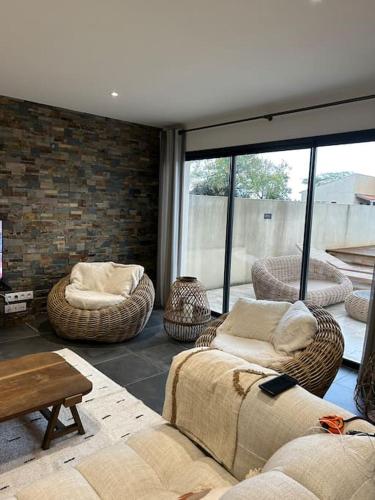 - un salon avec des canapés et des chaises ainsi qu'un mur en briques dans l'établissement Maison de charme avec piscine, à Aigrefeuille-dʼAunis