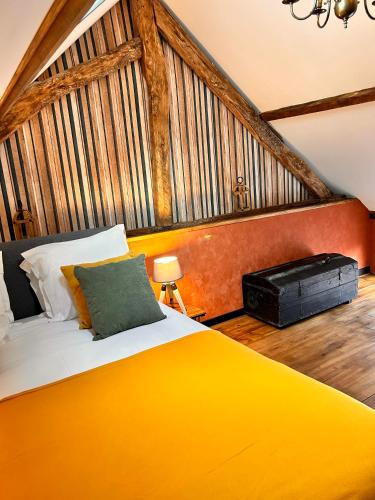 une chambre avec un grand lit avec une couverture jaune dans l'établissement La Grange Aux Hirondelles - Chambre Atelier, à Woignarue