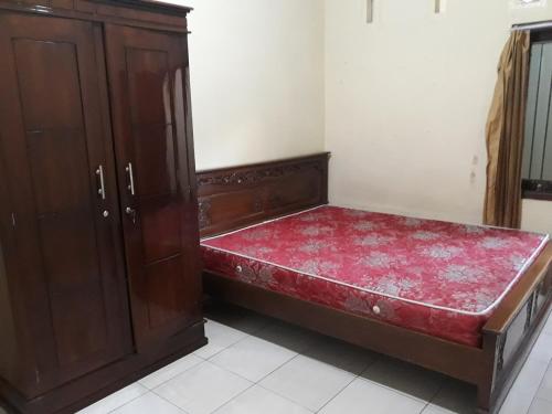 Ce lit se trouve dans un dortoir doté d'une armoire en bois. dans l'établissement Kost Cendana, à Kudus