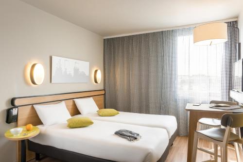 マシーにあるアパートホテル アダージョ アクセス パリ マッシー ガレのベッド2台とデスクが備わるホテルルームです。