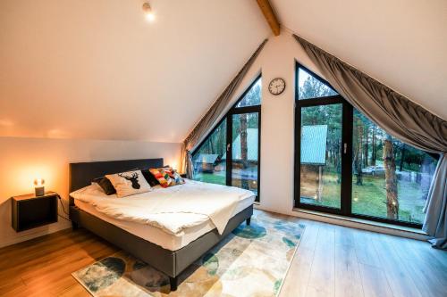 a bedroom with a bed and a large window at Heban Forest Cabin&SAUNA Starlink in Tomczyn