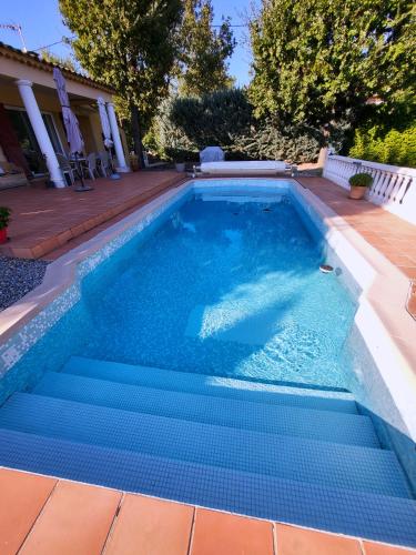 une piscine avec de l'eau bleue dans une cour arrière dans l'établissement Cosy rez-de-jardin de villa, à Brignoles