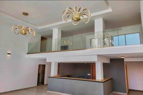 a living room with two chandeliers and a kitchen at Appartement F4 meublé à Dakar in Dakar